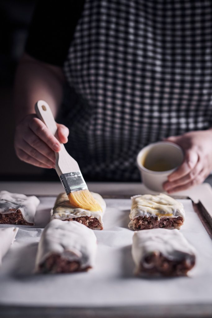 Brushing eggwash on sausage rolls